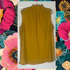 Sleeveless mustard blouse with ruffle neck.